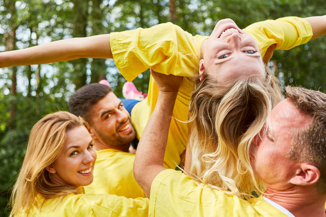 Eine Gruppenübung, mehrere Leute tragen eine Frau auf den Händen