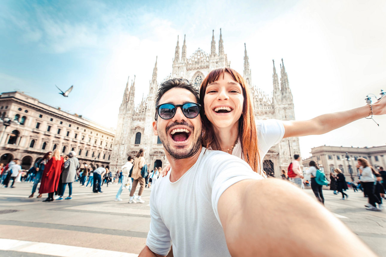 Zwei junge Menschen stehend vor eine Kirche und machen ein Selfie