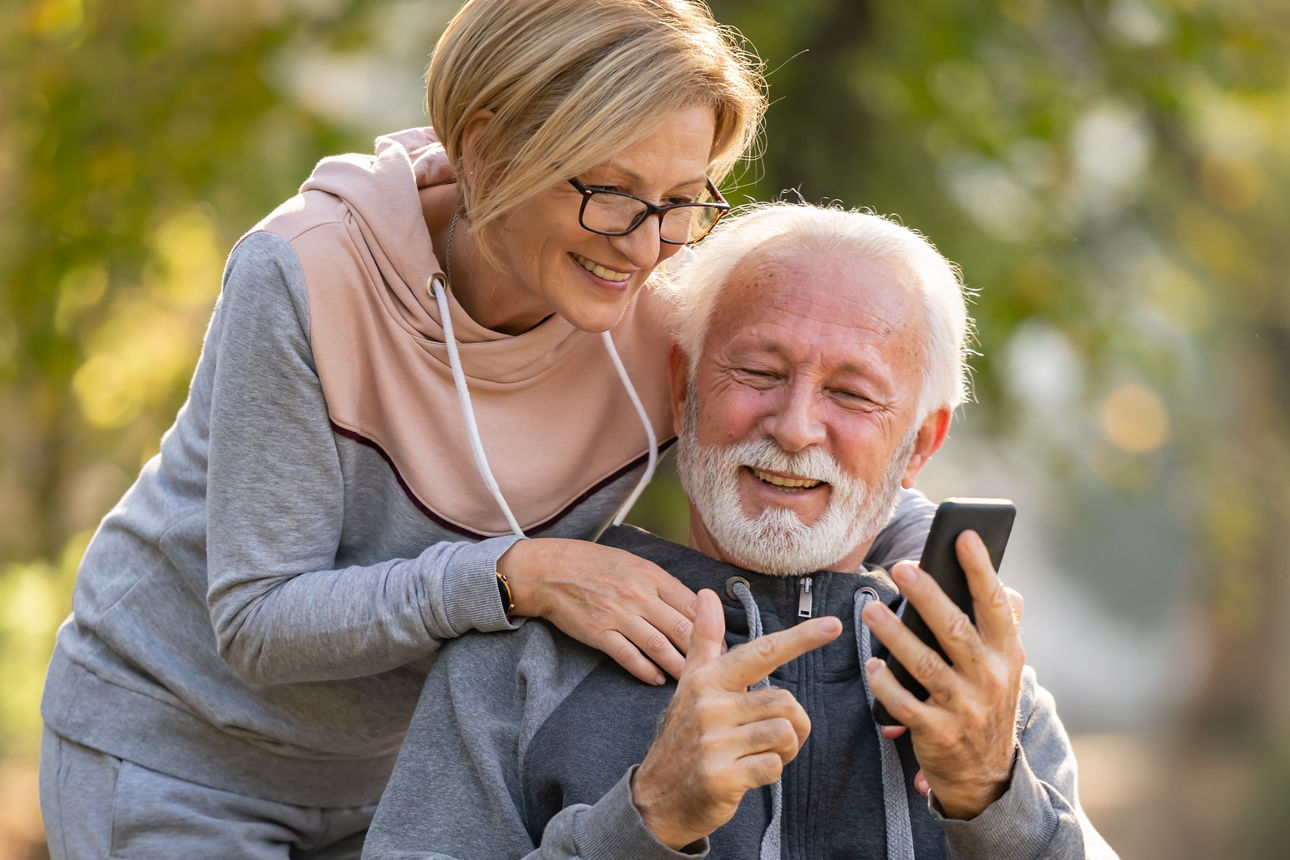 Ein Rentnerpaar, dass zusammen auf ein Handy schaut