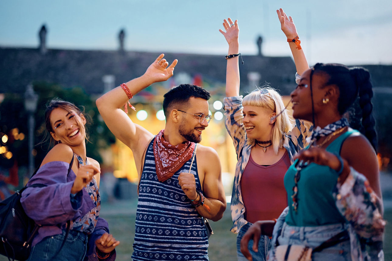 Vier junge Leute tanzen im Freien vor einer Bühne