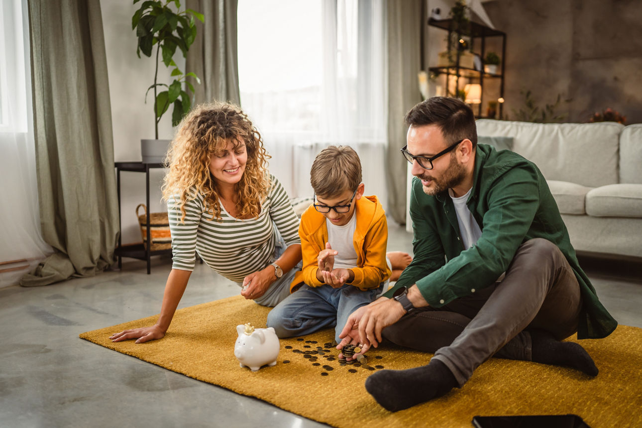 Eine Familie mit einem Kind sitzt auf einem Teppich in einem Zimmer und puzzelt