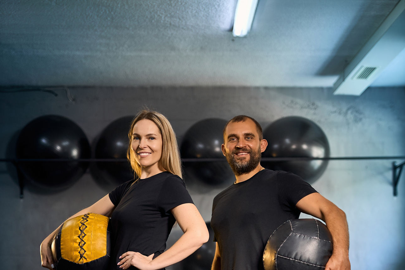 Eine Frau und ein Mann im Fitnessstudio mit einem Ball in der Hand