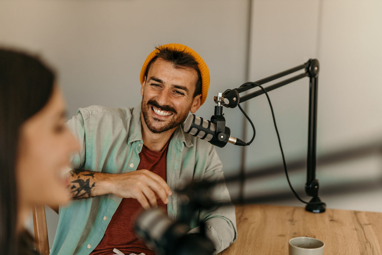Junger lächelnder Mann sitzt in einem Cafe und arbeitet am Laptop