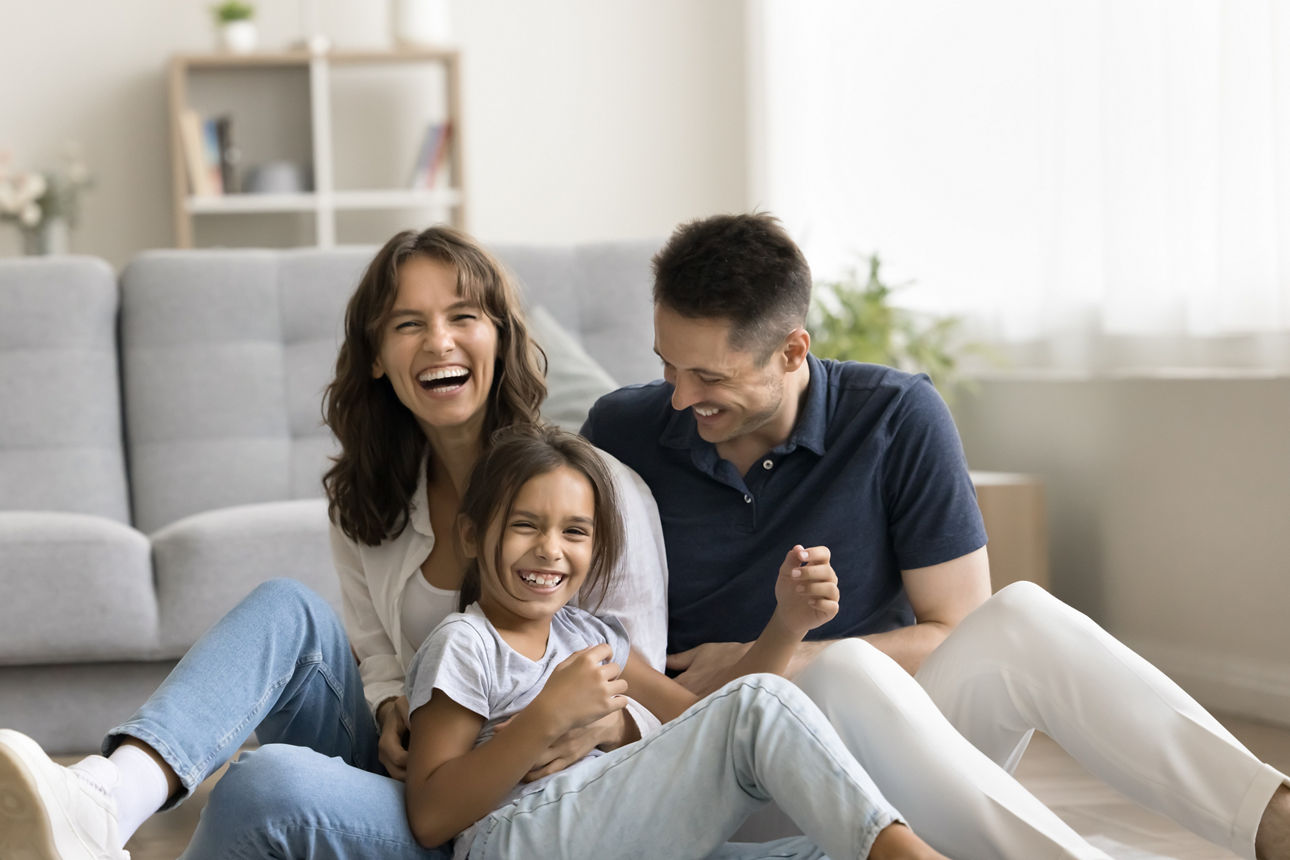 Sweet home. Laughing candid millennial spouses with preteen child mother father little daughter enjoy funny indoor activity messing tickling on floor with heating play in crazy naughty mood on weekend