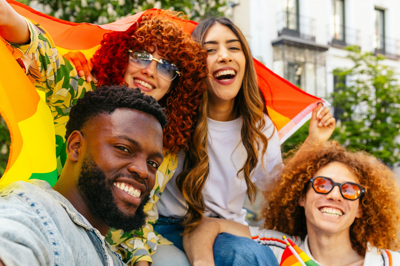 Eine Gruppe von jungen Menschen sitzt lachend auf einer Bank im Freien