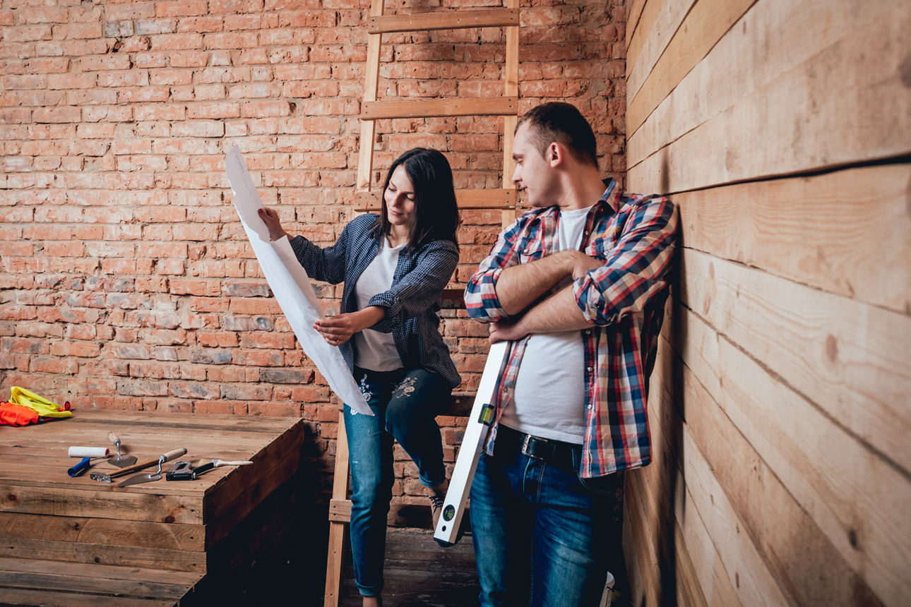 Eine Frau und ein Mann schauen sich gemeinsam einen Bau-Plan an.
