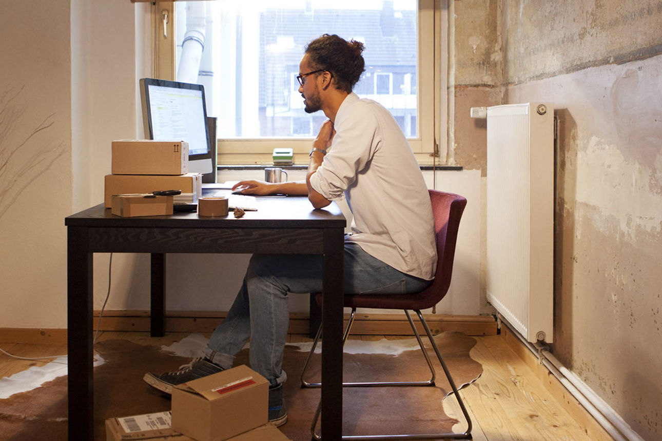 Ein junger Mann sitzt an einem PC am Schreibtisch