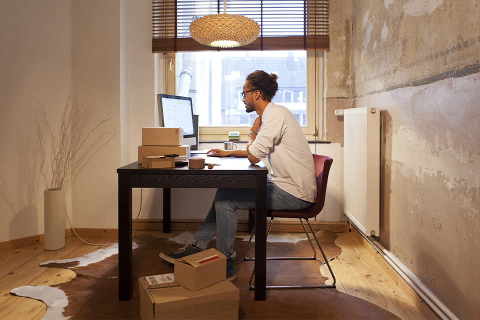 Mann sitzt an einem Tisch vor dem Computer