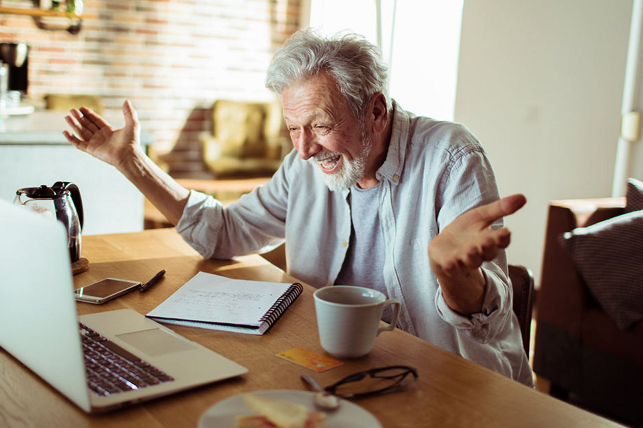 Ein Mann sitzt am Schreibtisch mit seinem Laptop.