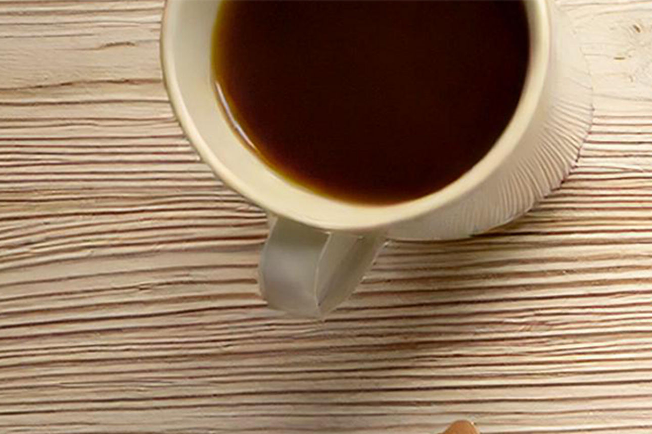 Tisch mit Tasse Kaffe und Notizbuch