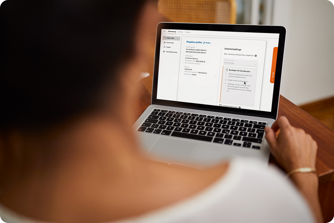Eine Frau hat ein Notbook auf dem Tisch und macht Online-Banking