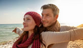 Frau hat Arme ausgebreitet mit Mann am Strand
