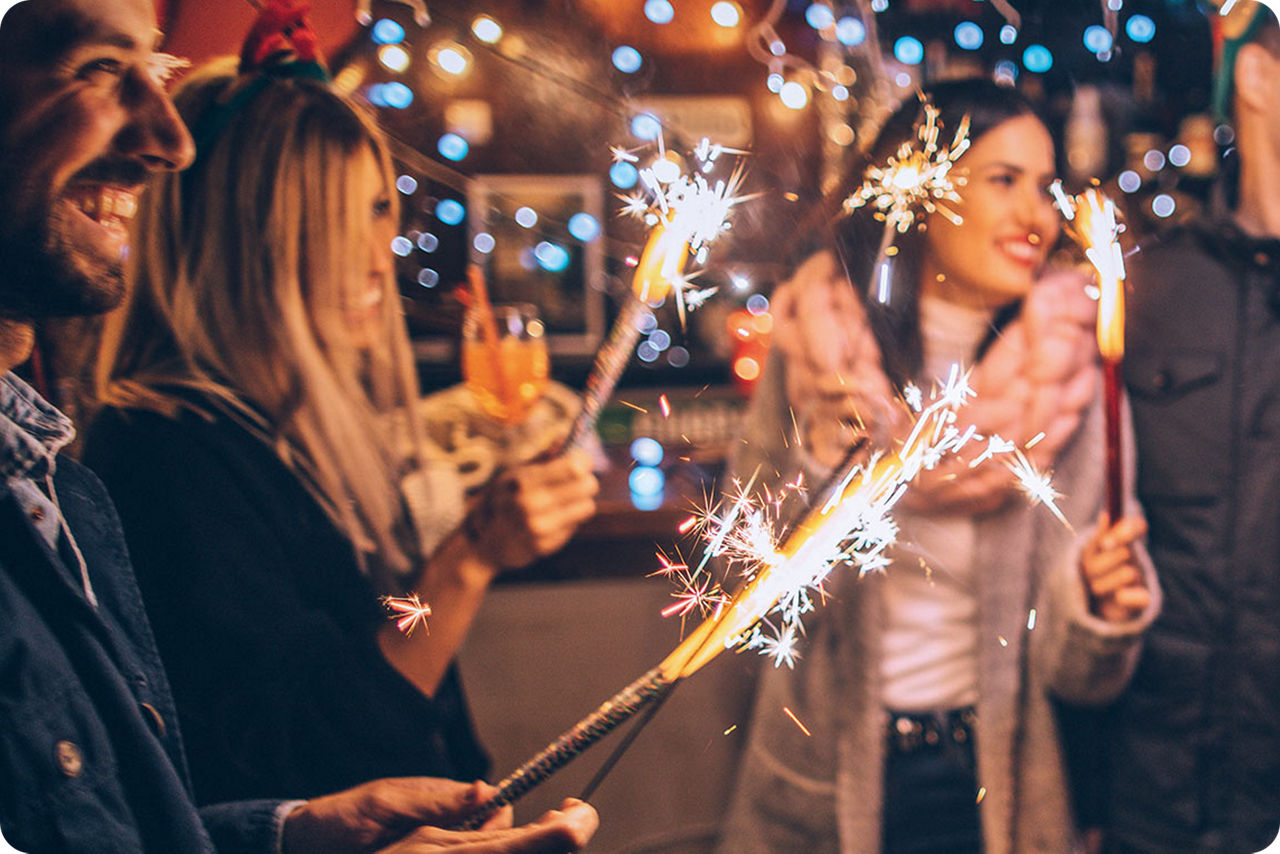 Eine Gruppe von Menschen stehen zusammen mit Wunderkerzen in den Händen und lachen