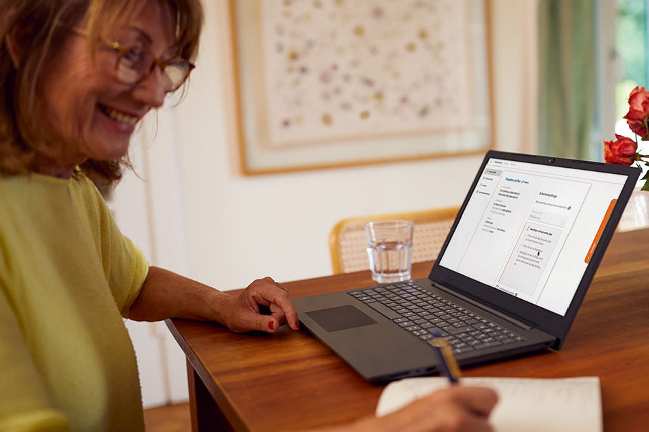  Frau sitzt am Tisch mit Laptop