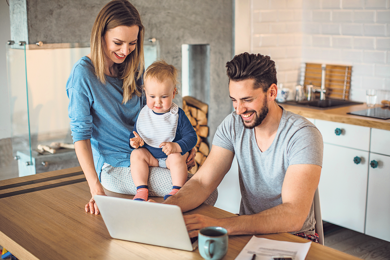 Eine junge Familie sitzt vor dem Laptop
