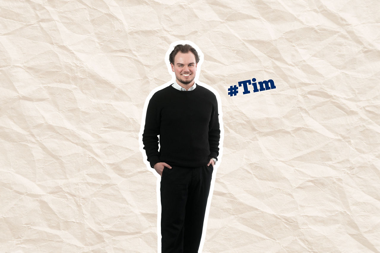 Ein lächelnder Tim in schwarzem Outfit auf zerknittertem Papierhintergrund, daneben ein blauer #Tim-Sticker.