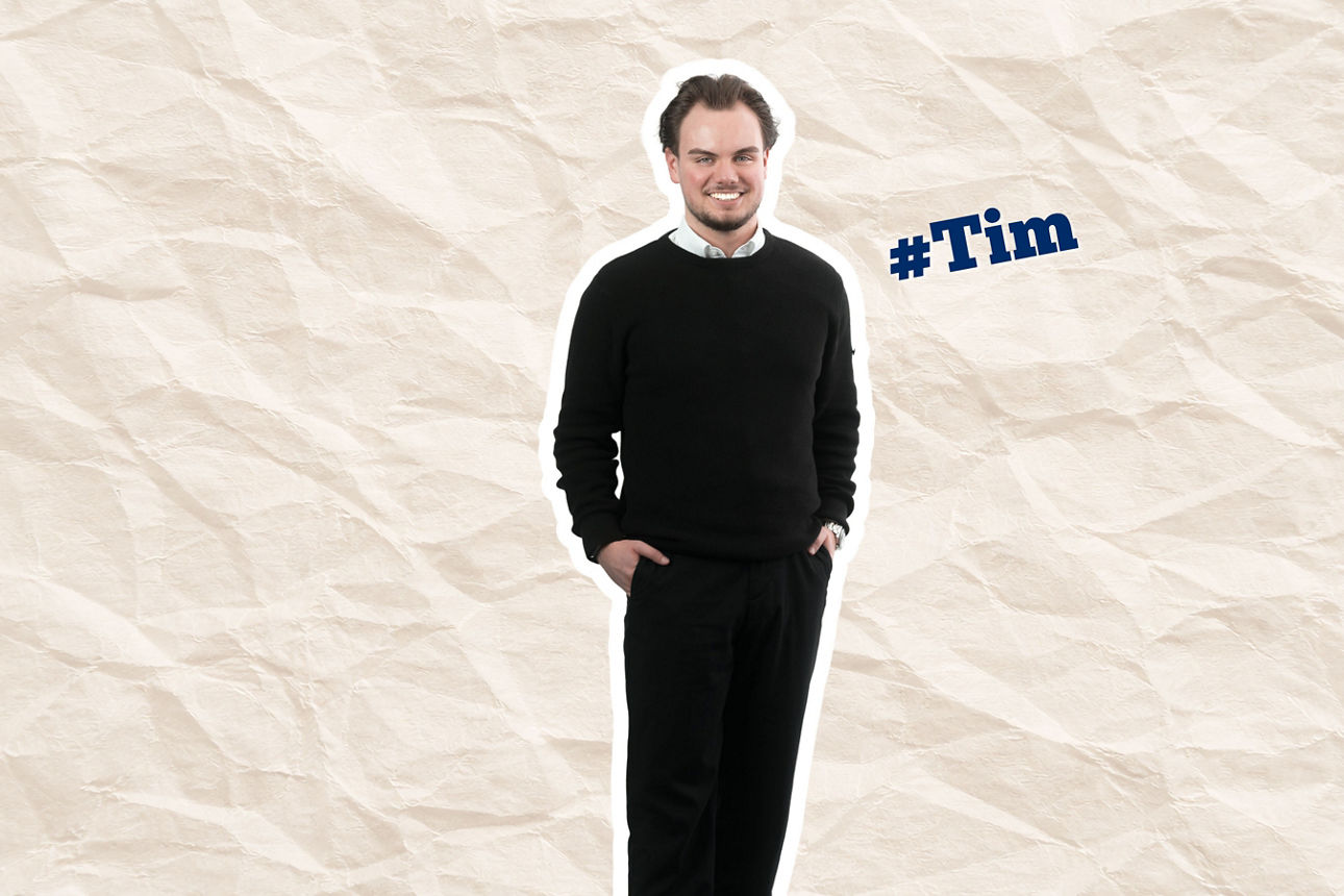 Ein lächelnder Tim in schwarzem Outfit auf zerknittertem Papierhintergrund, daneben ein blauer #Tim-Sticker.
