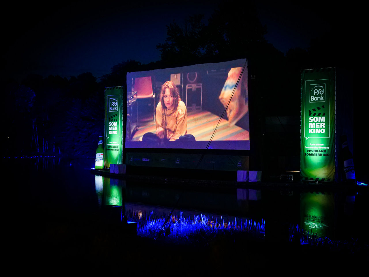 Fotografie der Leinwand beim PSD Bank Sommerkino auf dem ein Blockbuster zu sehen ist.