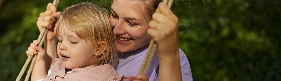Frau Schaukelt mit Kind im Garten