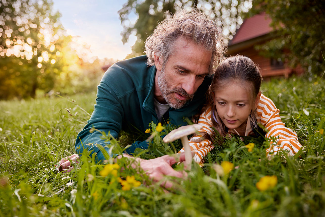 Vater und Tochter liegen in der Natur auf einer grünen Wiese
