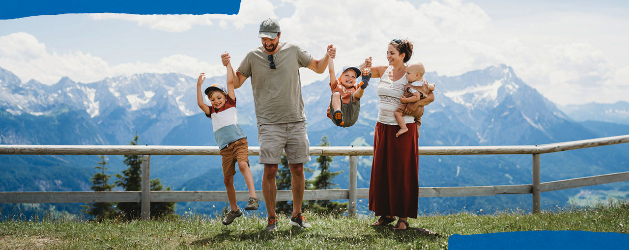 Eine fünfköpfige FAmilie hat Spaß vor einem Bergpanorama