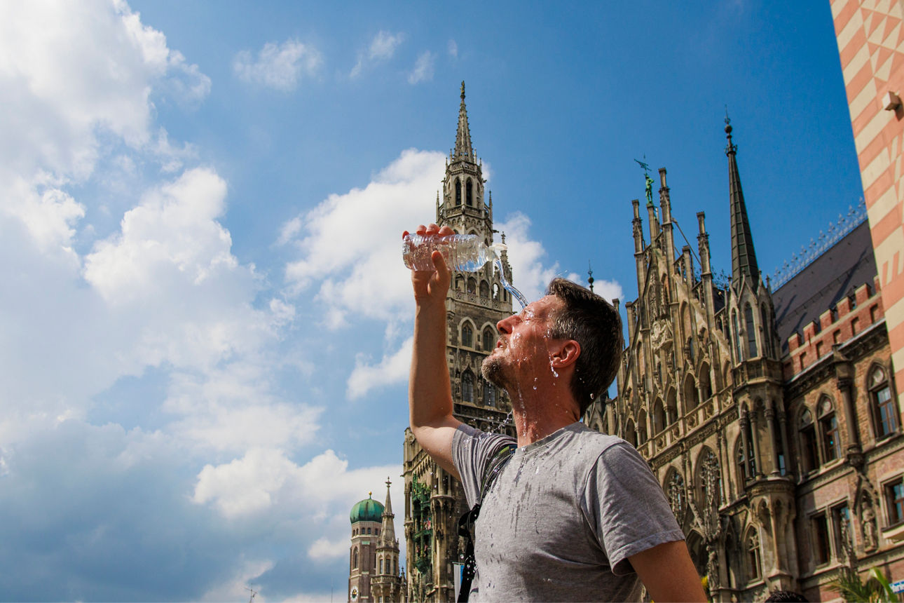 Ein offenbar überhitzter Mann auf dem Münchner Marienplatz schüttet sich den Inhalt einer Wasserflasche ins Gesicht..
