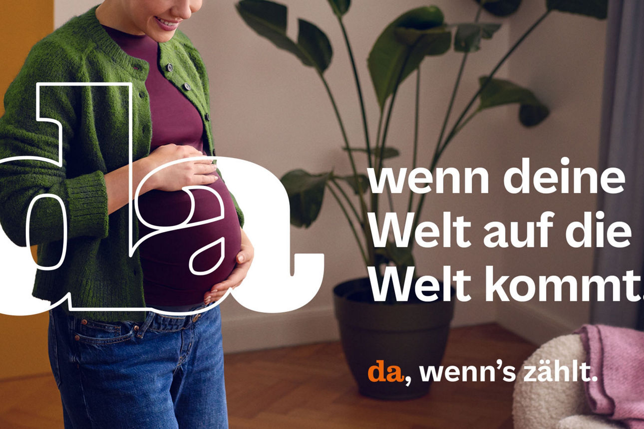 Eine Frau in freudiger Erwartung hält sich lächelnd ihren Bauch.