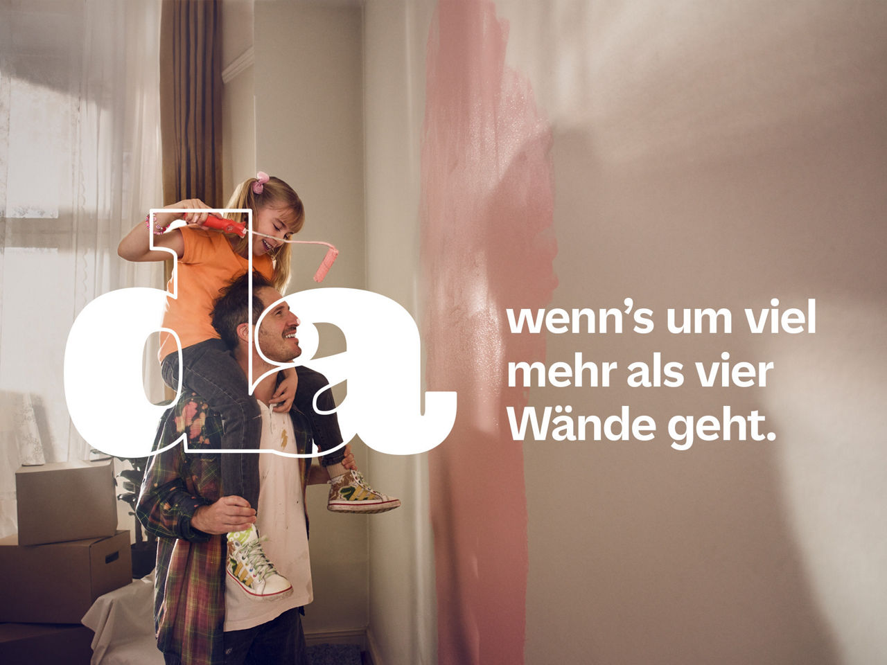 Ein Vater streicht mit seinem Sohn, den er auf den Schultern trägt, eine Wand.