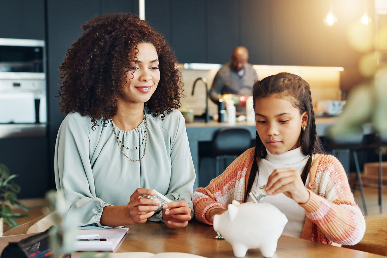 Patin füttert gemeinsam mit ihrem Patenkind ein Sparschwein als Symbol für die Wichtigkeit des Sparens für Patenkinder.
