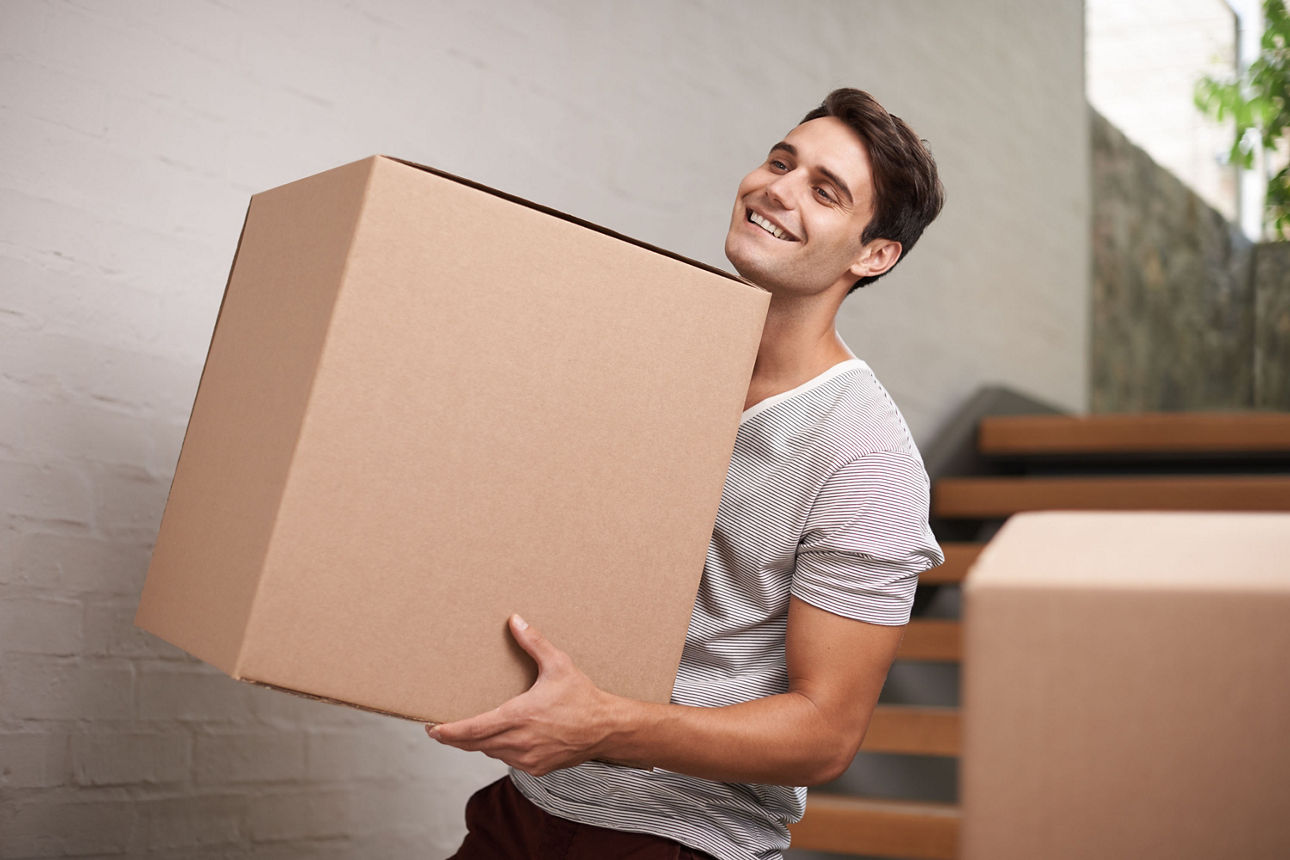 Ein junger Mann, der eine Kiste trägt, symbolisiert das Sparen für den Umzug der Kinder.