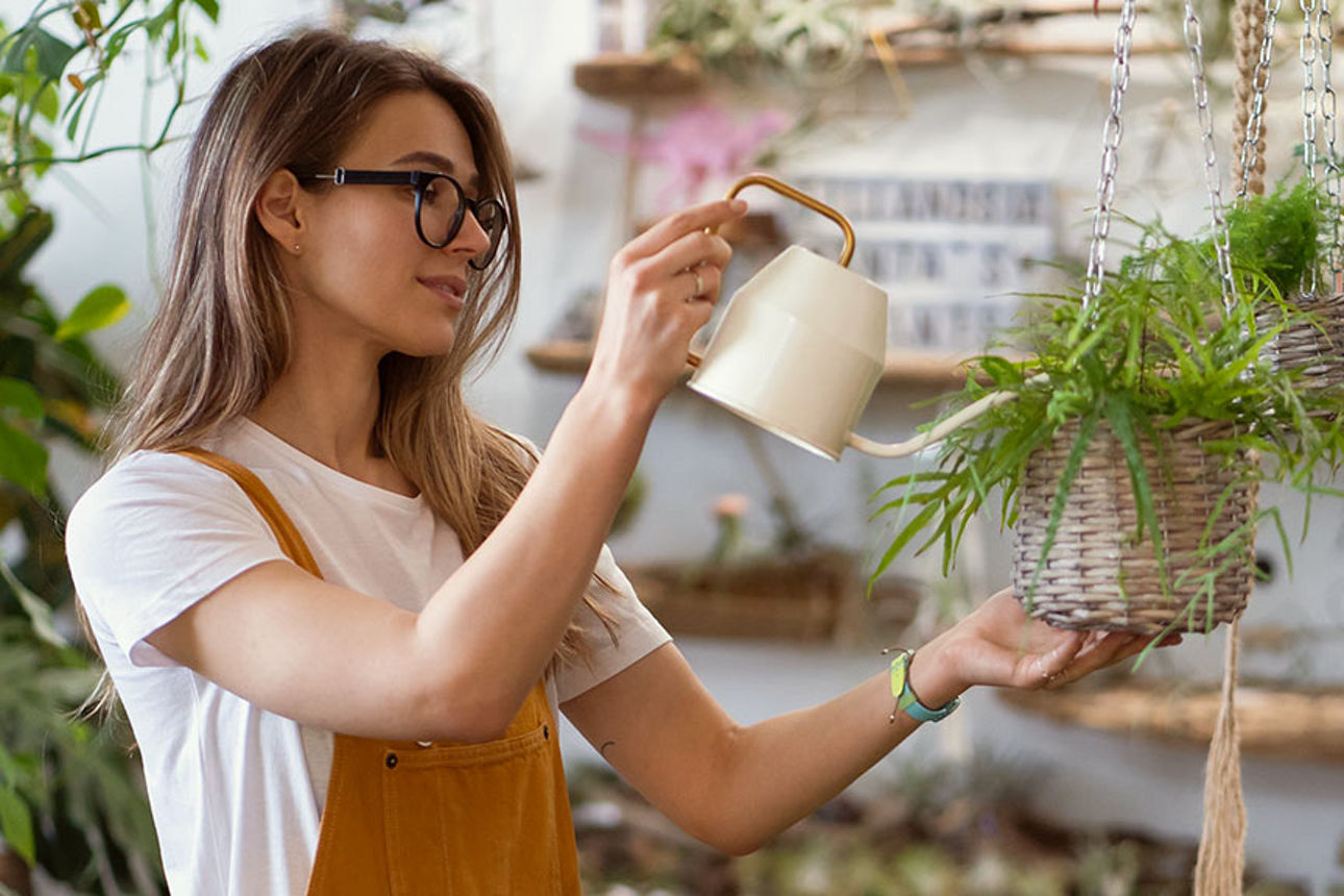 Junge Frau gießt Blumen