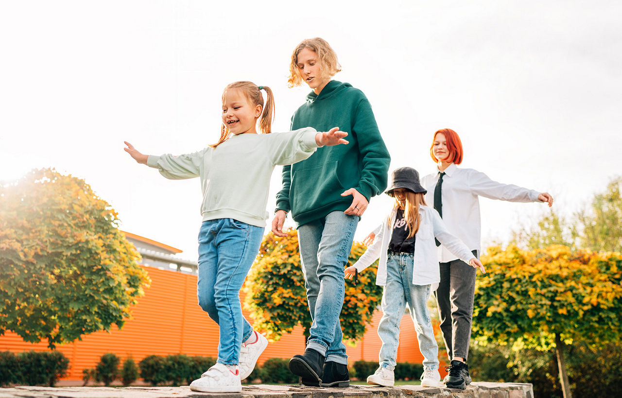 Kinder und Jugendliche balancieren auf einem Holzbalken