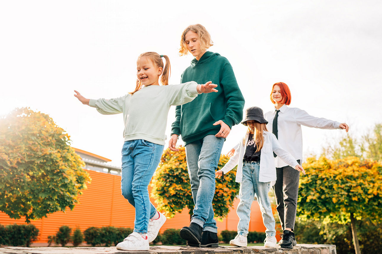 Unterschiedlich alte Kinder balancieren auf einem Balken