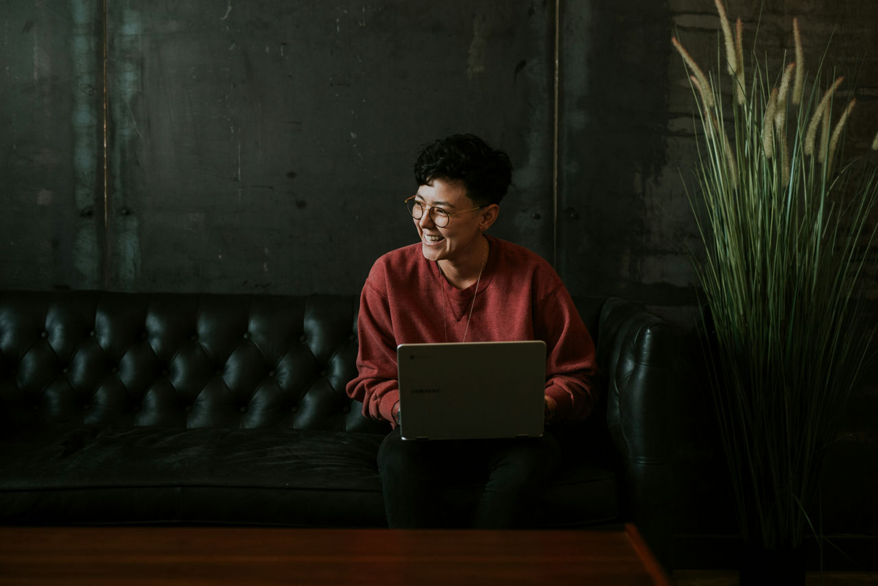 Frau sitzt auf Loungesofa und arbeitet am Laptop