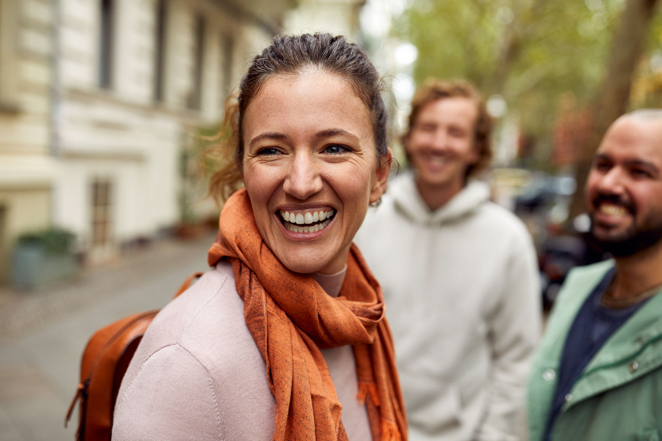 Eine Frau steht mit ihren Freunden auf der Straße und lacht