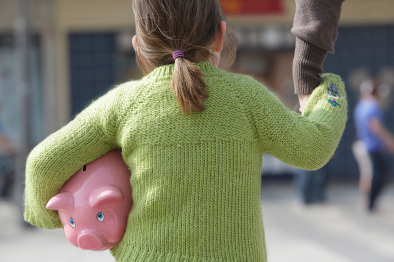 Kind mit Sparschwein auf dem Weg in die Bankfiliale