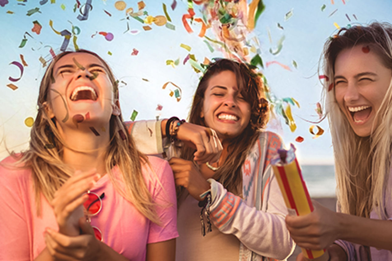 Drei junge Frauen stehen glücklich und lachend im Konfetti Regen