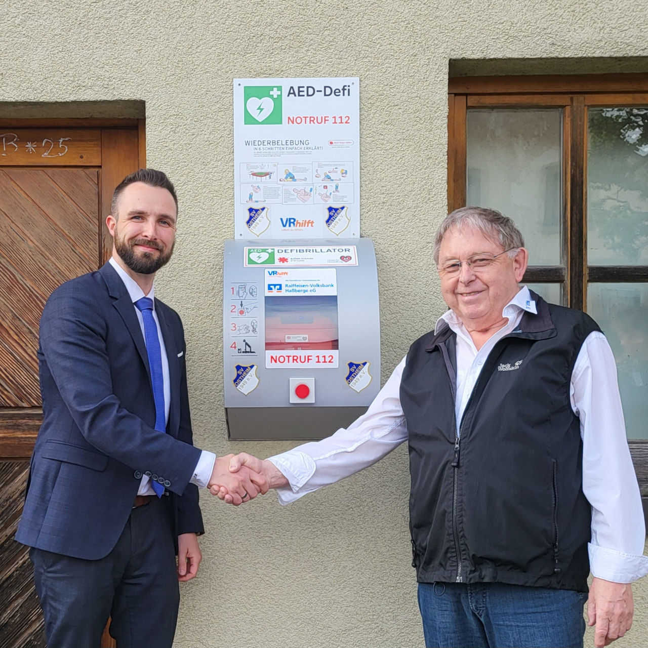 Vermögensberater Tobias Müller übergibt den Defibrillator an Karl-Heinz-Scheuring
