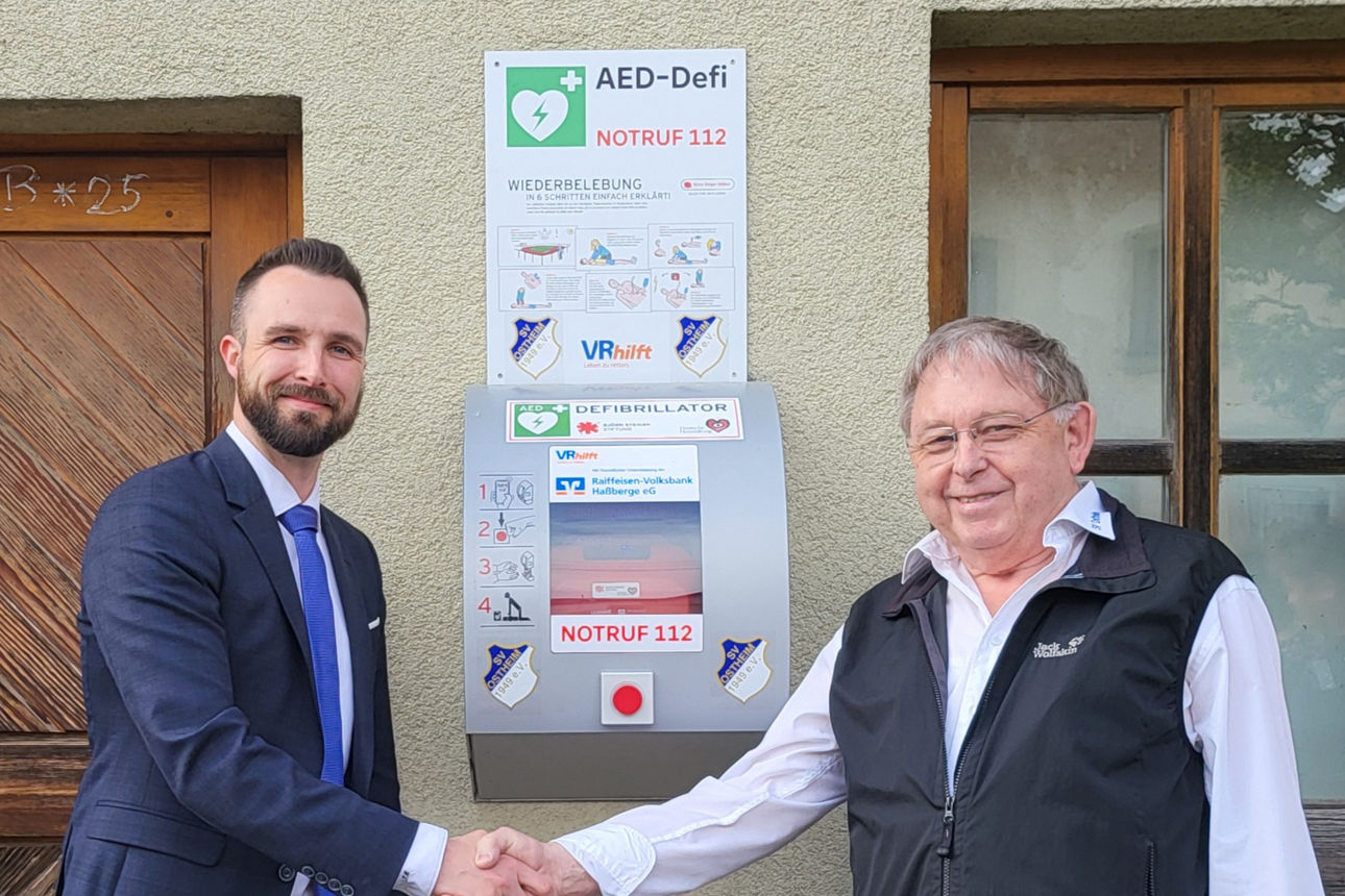 Vermögensberater Tobias Müller übergibt den Defibrillator an Karl-Heinz-Scheuring