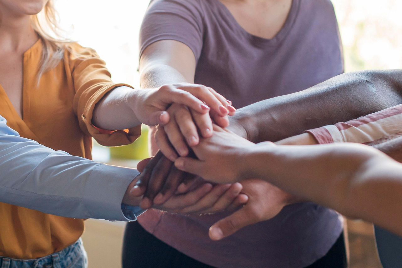 Teamgedanke - eine Gruppe Menschen haalten die Hände zusammen
