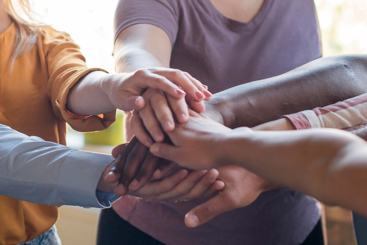 Teamgedanke - eine Gruppe Menschen haalten die Hände zusammen