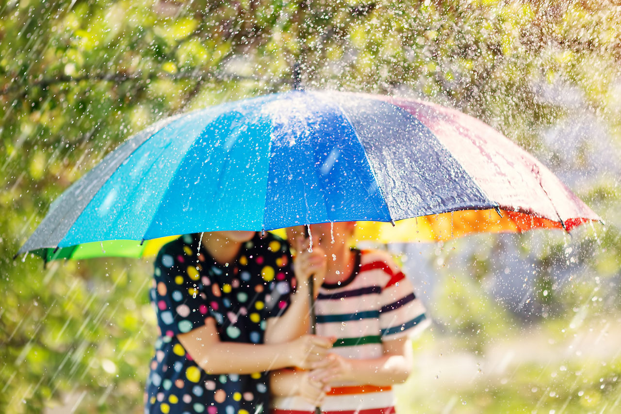 2 Kinder unter Regenschirm im Sommerregen