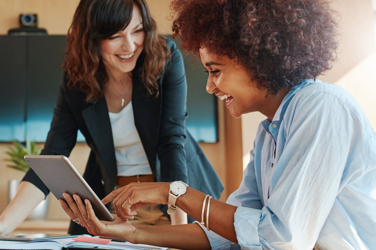 Zwei Businessfrauen am Schreibtisch schauen auf ein Tablet