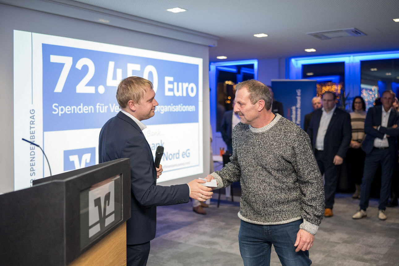 Ein Mann mit einem Mikrofon wärend er einem Mann die Hand reicht.