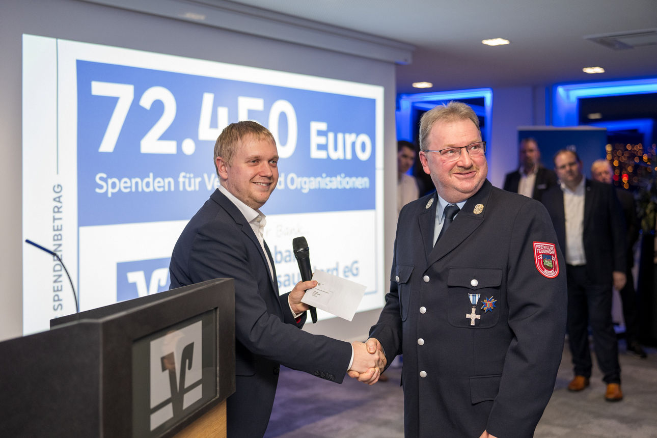 Ein Mann mit einem Mikrofon wärend er einem Mann die Hand reicht.