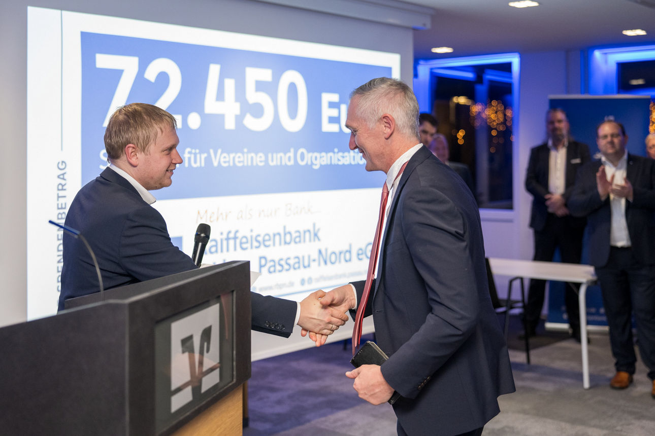 Ein Mann mit einem Mikrofon wärend er einem Mann redet.