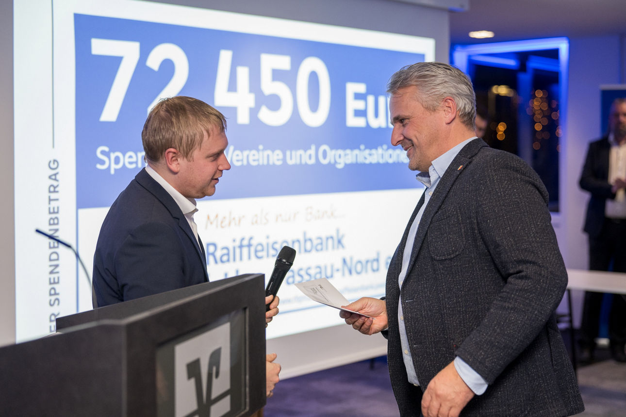 Ein Mann mit einem Mikrofon wärend er einem Mann redet.