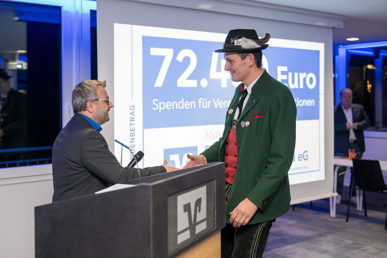 Ein Mann mit einem Mikrofon wärend er einer Frau die Hand reicht.