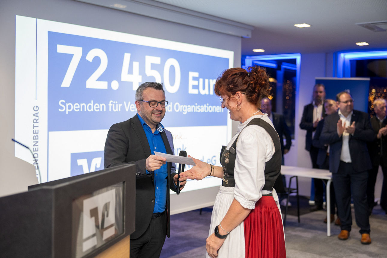 Ein Mann mit einem Mikrofon wärend er einer Frau die Hand reicht.