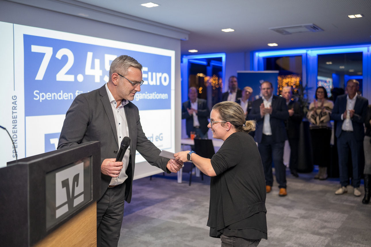 Ein Mann mit einem Mikrofon wärend er einer Frau die Hand reicht.